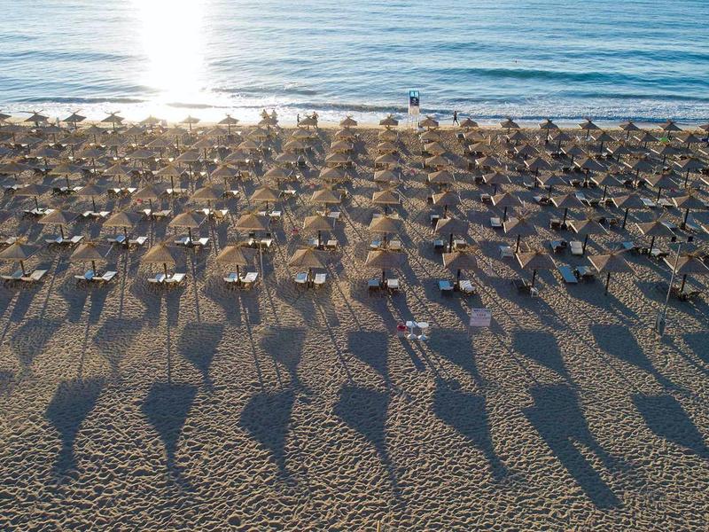 Plage avec de nombreux parasols et chaises longues au lever du jour au bord de la mer