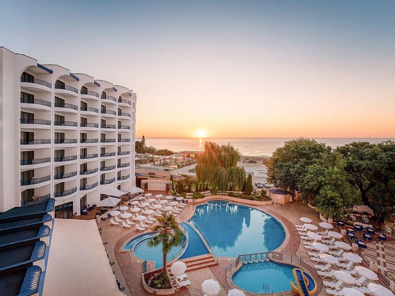 Hôtel avec piscine extérieure, transats et vue sur la mer au coucher du soleil