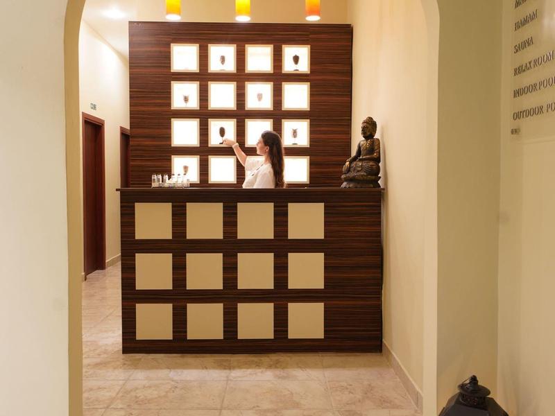 Espace de réception lumineux avec comptoir sombre, étagères murales décoratives et statue.