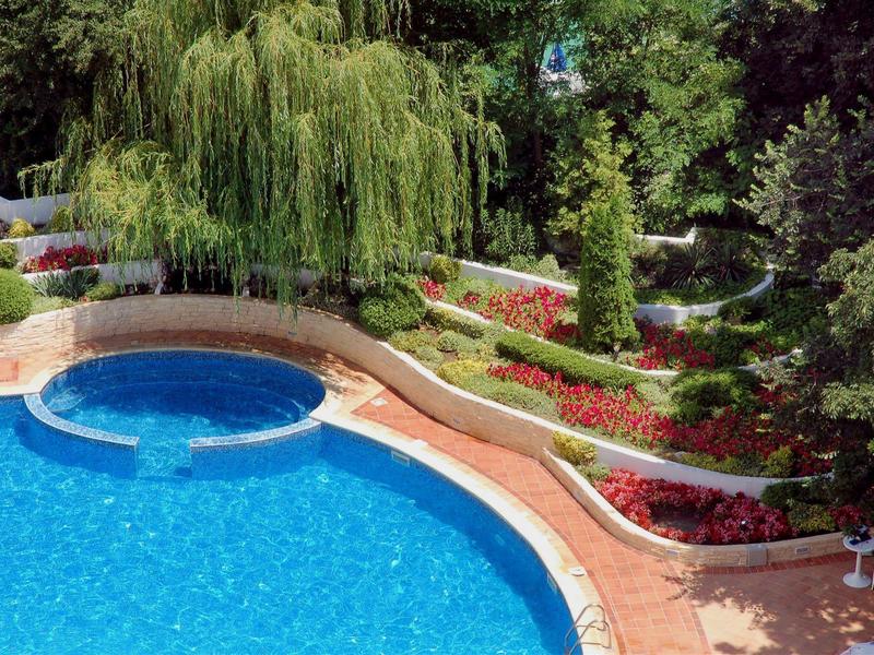 Piscine avec jacuzzi rond et jardin soigné avec buissons et fleurs