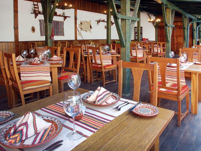 Restaurant rustique avec tables en bois, nappes rayées et serviettes pliées.