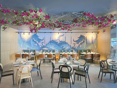 Elegant restaurant met blauwe muurkunst en bloemen aan het plafond.