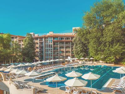 Velký bazén s mnoha bílými slunečníky a lehátky před hotelem.