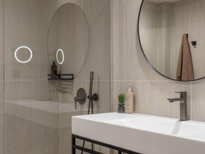 Moderne badkamer met grote rechthoekige wastafel, ronde spiegel en inloopdouche.