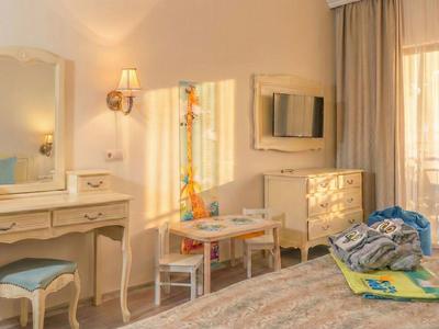 Lichte hotelkamer met make-up tafel, tv en balkon met gordijnen.