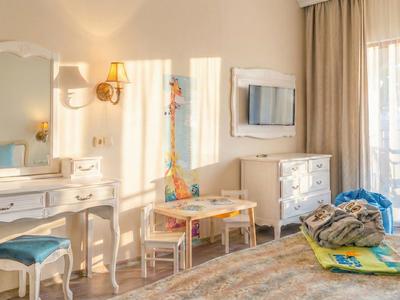 Lichte hotelkamer met kaptafel, kinder tafel, stoelen en kleurrijk speelgoed.