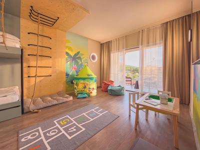 Hell eingerichteter Kinderspielraum mit Etagenbett, Sitzkissen und Blick auf Balkon.