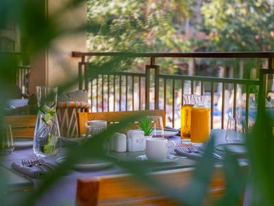 Gedeckter Tisch auf Balkon mit Glas, Orangensaft und Blick auf Bäume.
