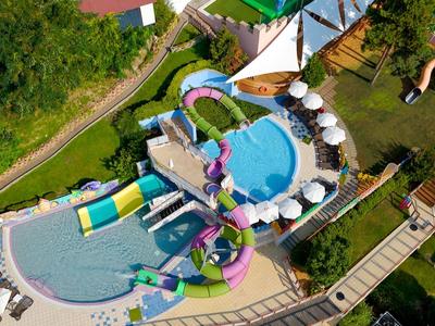 Wasserpark mit mehreren Pools, Wasserrutschen und Sonnenschirmen in einer Hotelanlage.