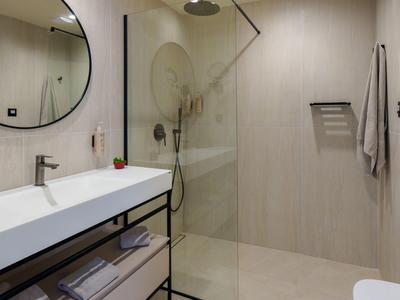 Modernes Badezimmer mit begehbarer Dusche, großem Spiegel und Doppelwaschbecken.
