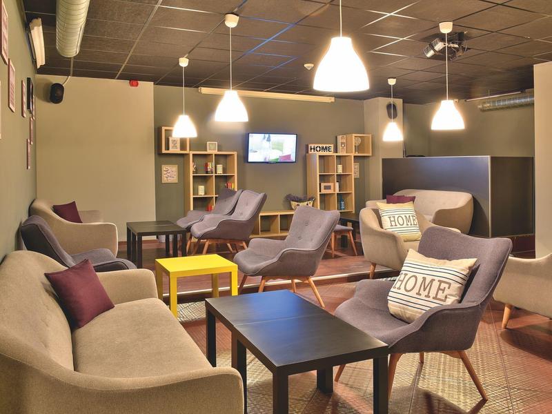 Gezellige lounge met banken, stoelen en tafels onder warm licht.