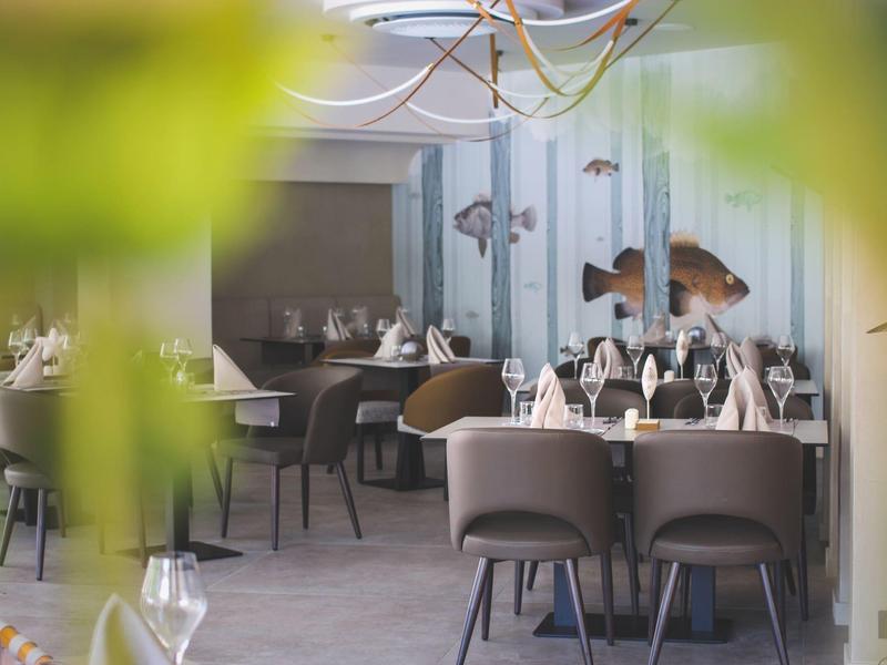 Elegant restaurant met modern design, gedekte tafels en visdecoraties aan de muur.