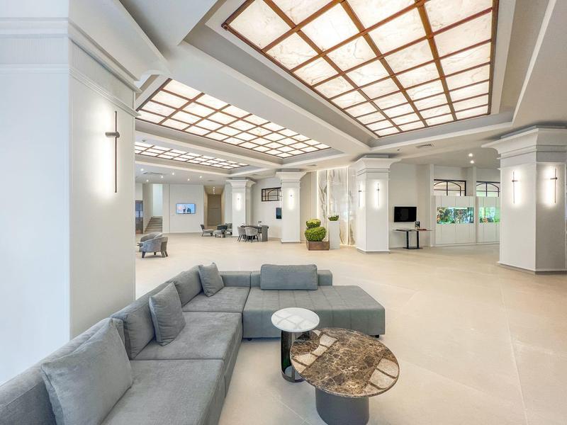 Lichte, moderne hotel lobby met zithoeken en groot plafondlicht.