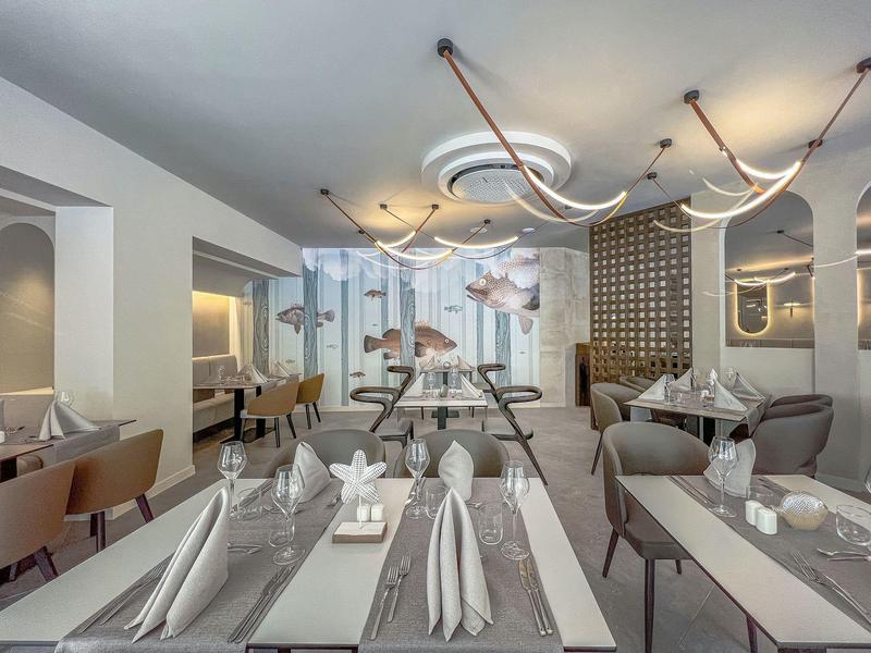 Elegant restaurant met modern design, gedekte tafels en decoratieve verlichting.