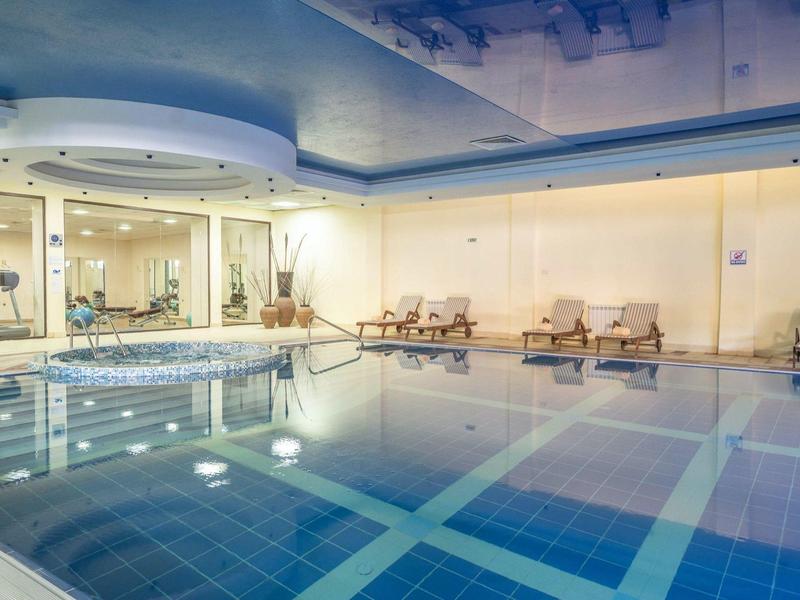 Binnenzwembad met blauw water, ligstoelen en een ontspannen sfeer in een hotel.