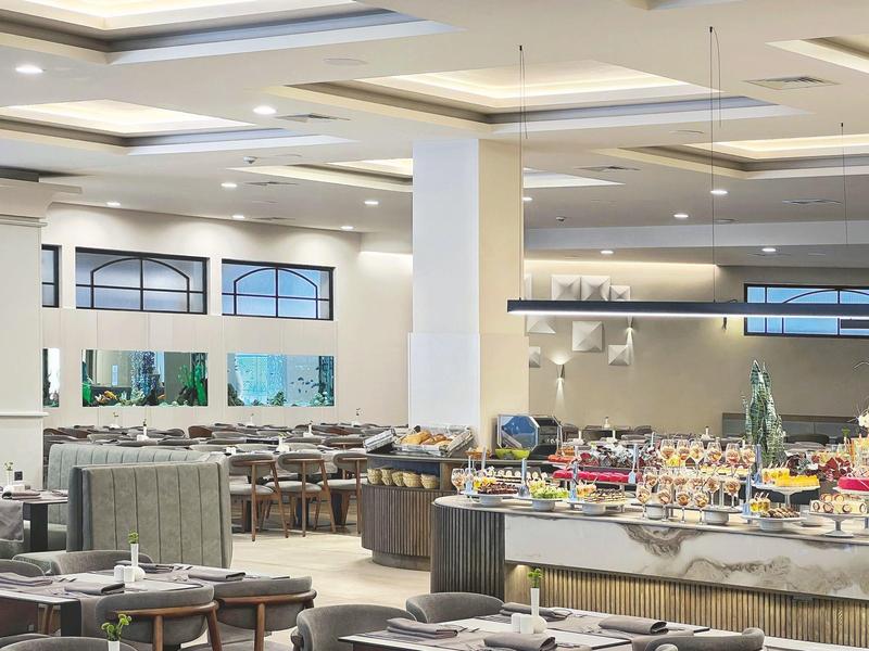 Moderne hotel eetzaal met buffetstation en gedekte tafels in een lichte inrichting.