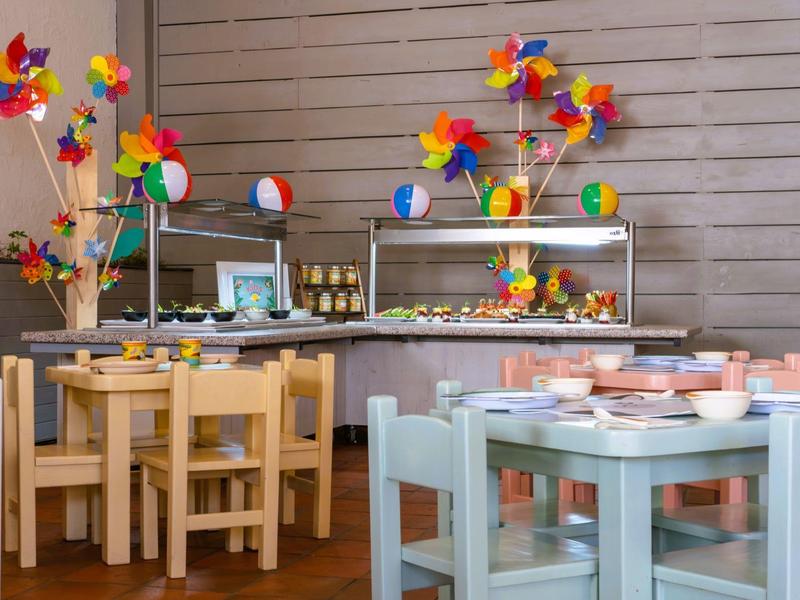 Kleurrijke windmolentjes versieren tafels in een gezellig restaurant met houten vloer en lambrisering.