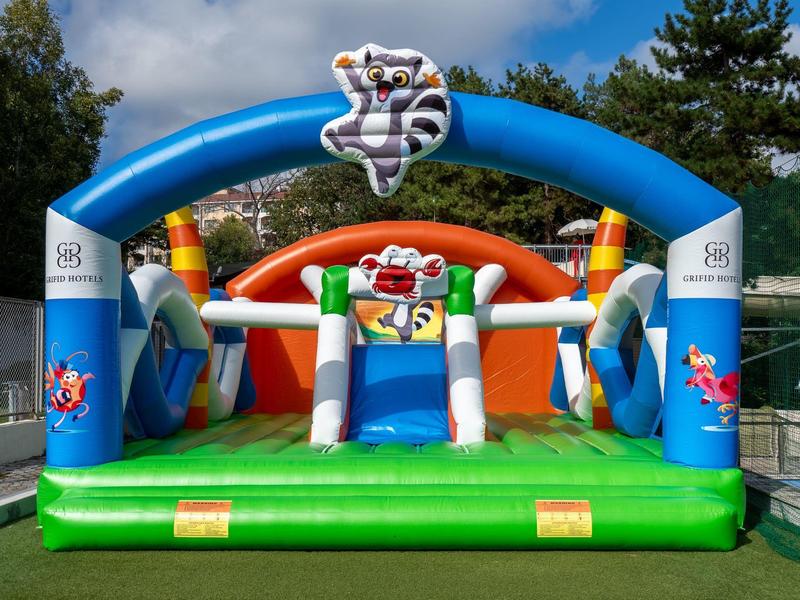 Kleurrijk opblaasbaar springkasteel met zebrapatroon buiten op groen gras.