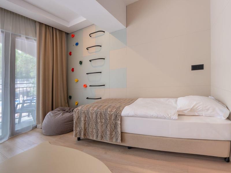 Moderne hotelkamer met eenpersoonsbed, deken, zitzak en balkon met uitzicht naar buiten.