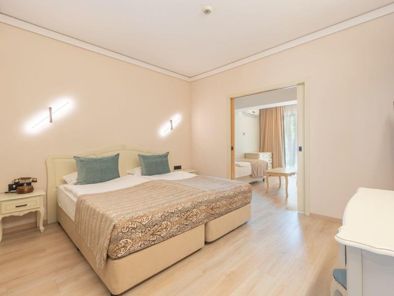 Lichte tweepersoonskamer met twee bedden, nachtkastjes en uitzicht op aangrenzende kamer.