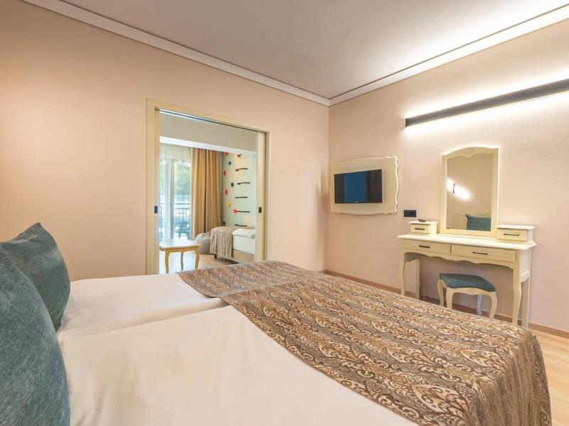 Modern hotelkamer met tweepersoonsbed, tv en grote spiegel met make-up tafel.