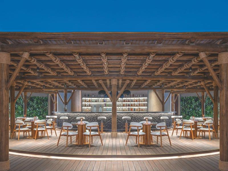 Open eetruimte met houten dak en ronde tafels in een hotel.