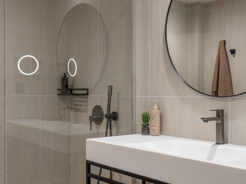 Moderne badkamer met grote rechthoekige wastafel, ronde spiegel en inloopdouche.