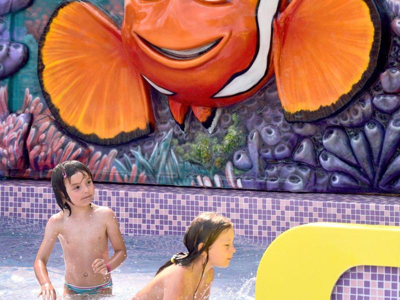 Twee kinderen die in het zwembad spelen met een grote clownvismuur in de achtergrond.