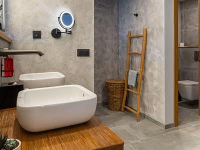 Modernes Badezimmer mit zwei weißen Waschbecken, Holztisch und grauen Wänden.