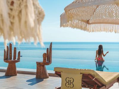 Beach terrace with hand-shaped chairs, lounge chair, and sunshade by the sea.