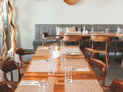 Modern dining area with wooden tables, chairs, and decorative wall baskets.