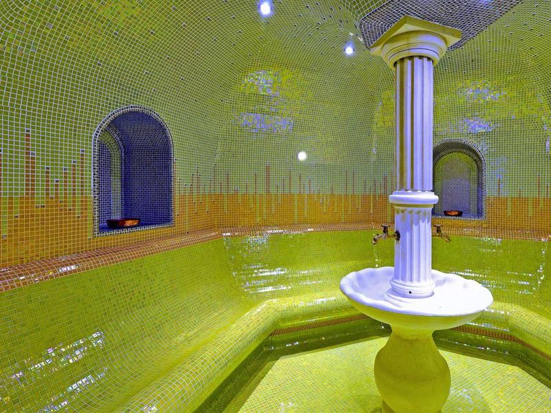 Interiér žluté parní lázně se sloupy a lavicemi