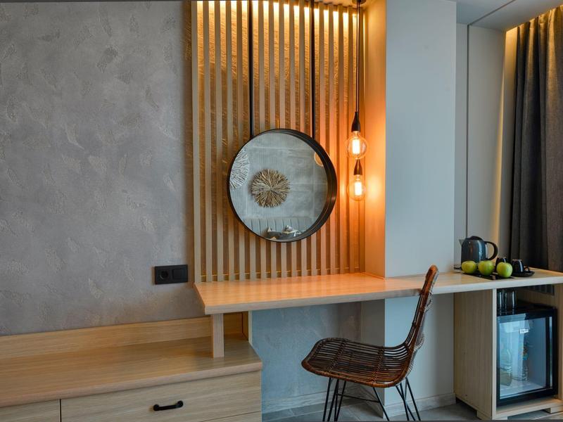 Moderní pracovní prostor v hotelu se stěnovou lampou, dřevěnými panely a proutěnou židlí