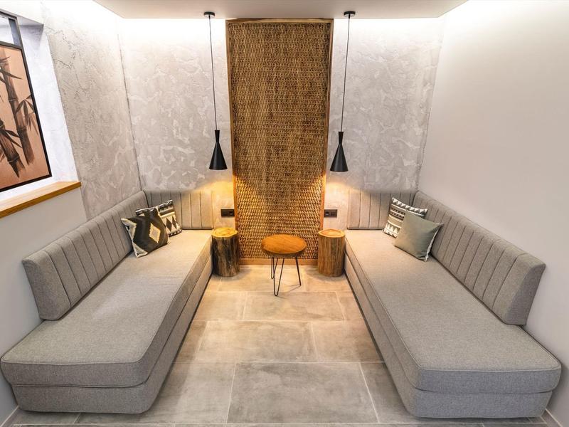 Moderní posezení se dvěma šedými pohovkami, polštáři a teplým osvětlením.