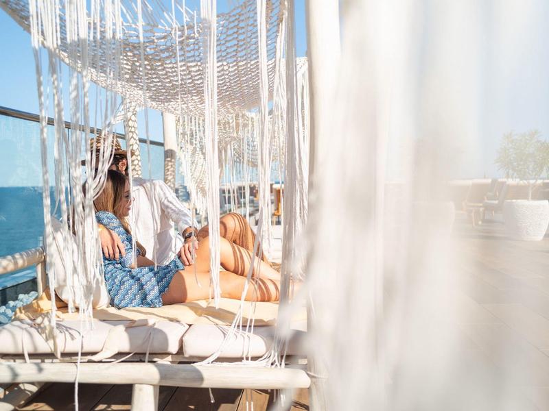 Žena odpočívá v závěsném křesle za jasné modré oblohy.