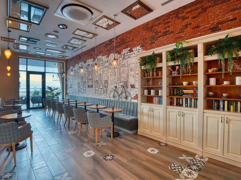 Moderní snídaňová místnost s židlemi, stoly a dekorativní cihlovou zdí v hotelu.