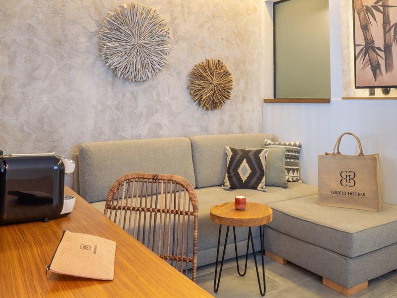 Pohodlný čtecí koutek s pohovkou, ratanovým křeslem a nástěnnou dekorací.