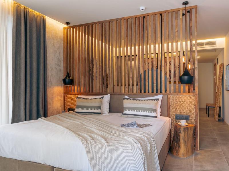 Moderně zařízený hotelový pokoj s manželskou postelí a dřevěnou příčkou.