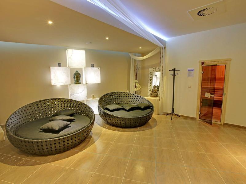 Moderní lounge s kulatým posezením a osvětlenými dekorativními stěnami v světlé místnosti.