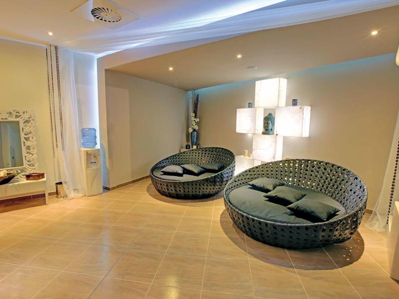 Moderní lounge prostor s kulatými proutěnými křesly, polštáři a teplým osvětlením v hotelu.