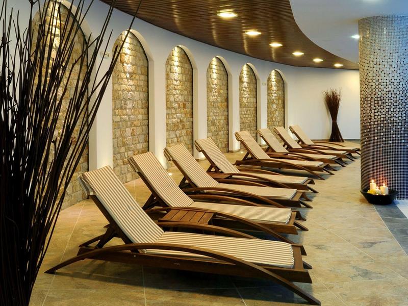 Moderní lehátka v elegantním spa s prohnutým dřevěným stropem.