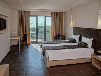 Modernes Hotelzimmer mit zwei Einzelbetten, Schreibtisch, Fernseher und Balkon mit Ausblick.