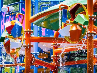 Bunte Wasserbahn mit Schaufelrädern, Eimern und Spritzdüsen in einem Wasserpark.