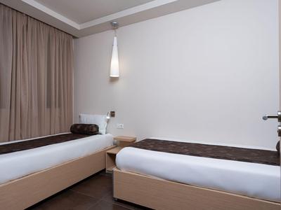 Two single beds with white linens in a calm, modern hotel room.