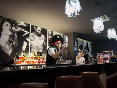 Bartender serving drinks in a modern bar with black and white portraits on the wall.