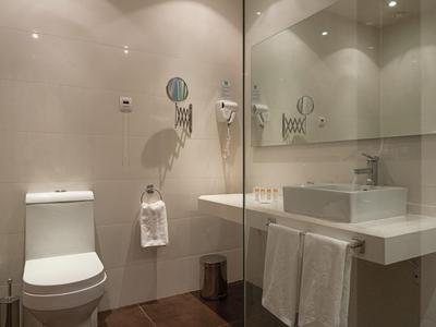 Modern hotel bathroom with white toilet, rectangular sink, and large wall mirror.