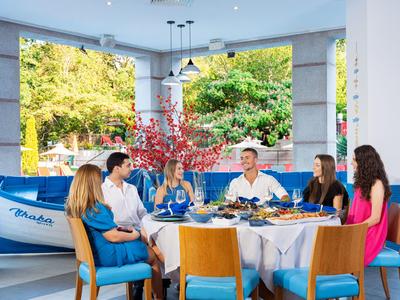 Six people sit around a round table with food in a bright, modern restaurant.