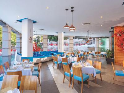 Brightly lit modern restaurant area with tables, chairs, and large windows.
