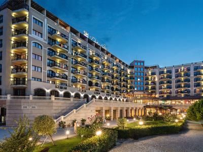 Large modern hotel with balconies and atmospheric lighting at dusk.