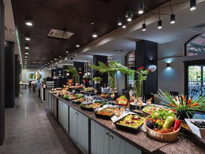 A buffet with a variety of arranged dishes and fresh fruits in a modern hotel restaurant.